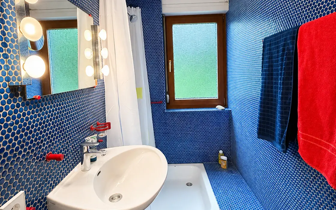 Duschbad mit blauem Mosaik und rundem Waschbecken